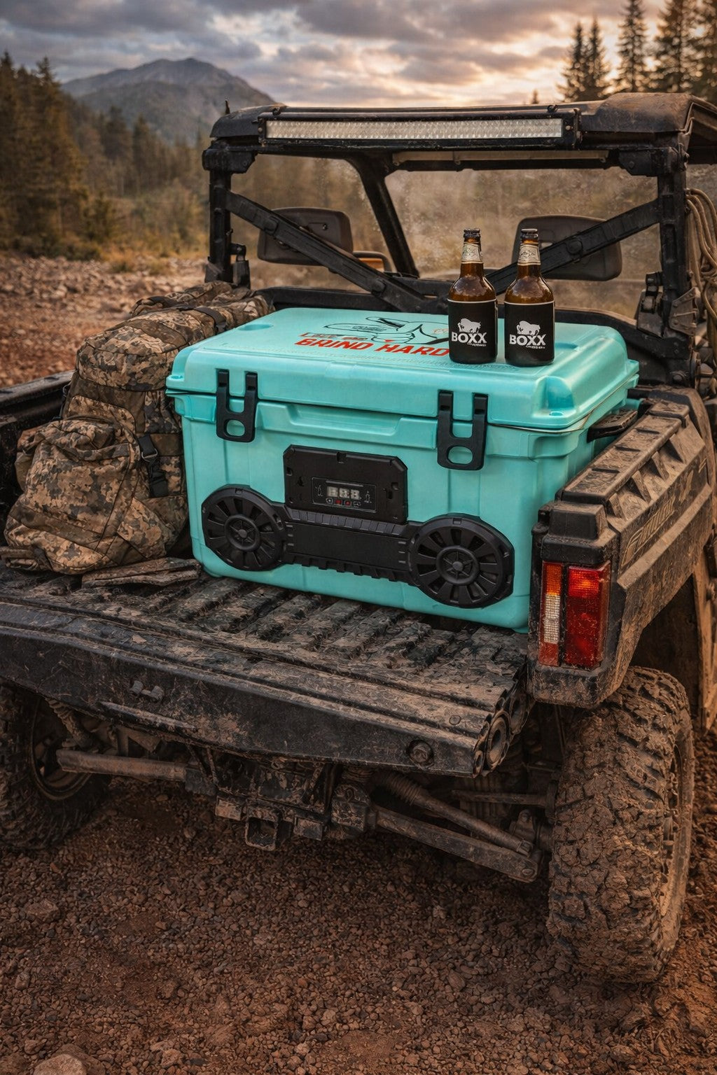 Teal Dual Hound Boxx Bluetooth cooler speaker in UTV bed during outdoor mountain adventure
