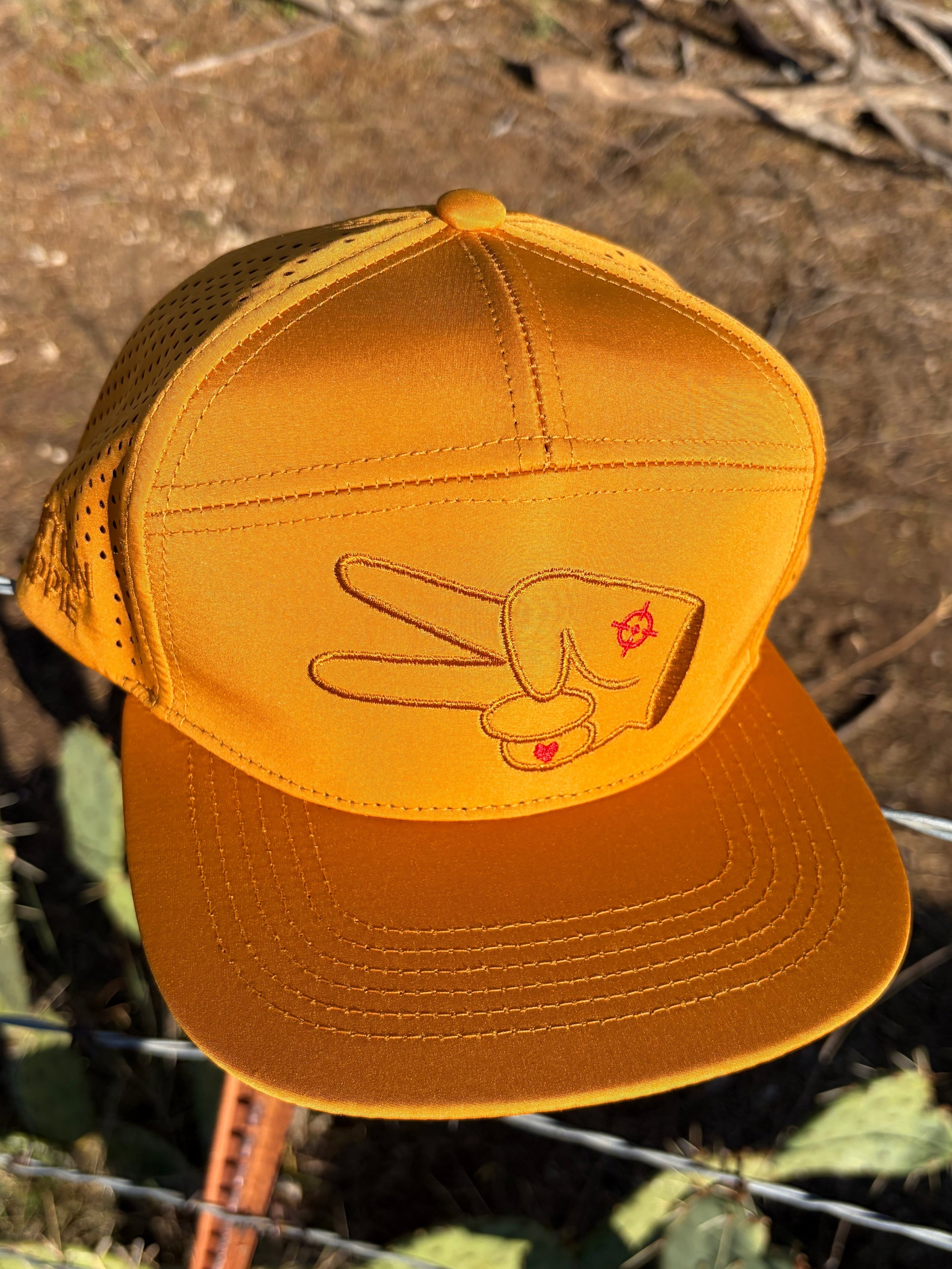 Angled top view of Hustlin Hippie Signature Burnt Orange Hydro Snapback Hat featuring embroidered signature hand logo and performance hydro material in outdoor desert setting