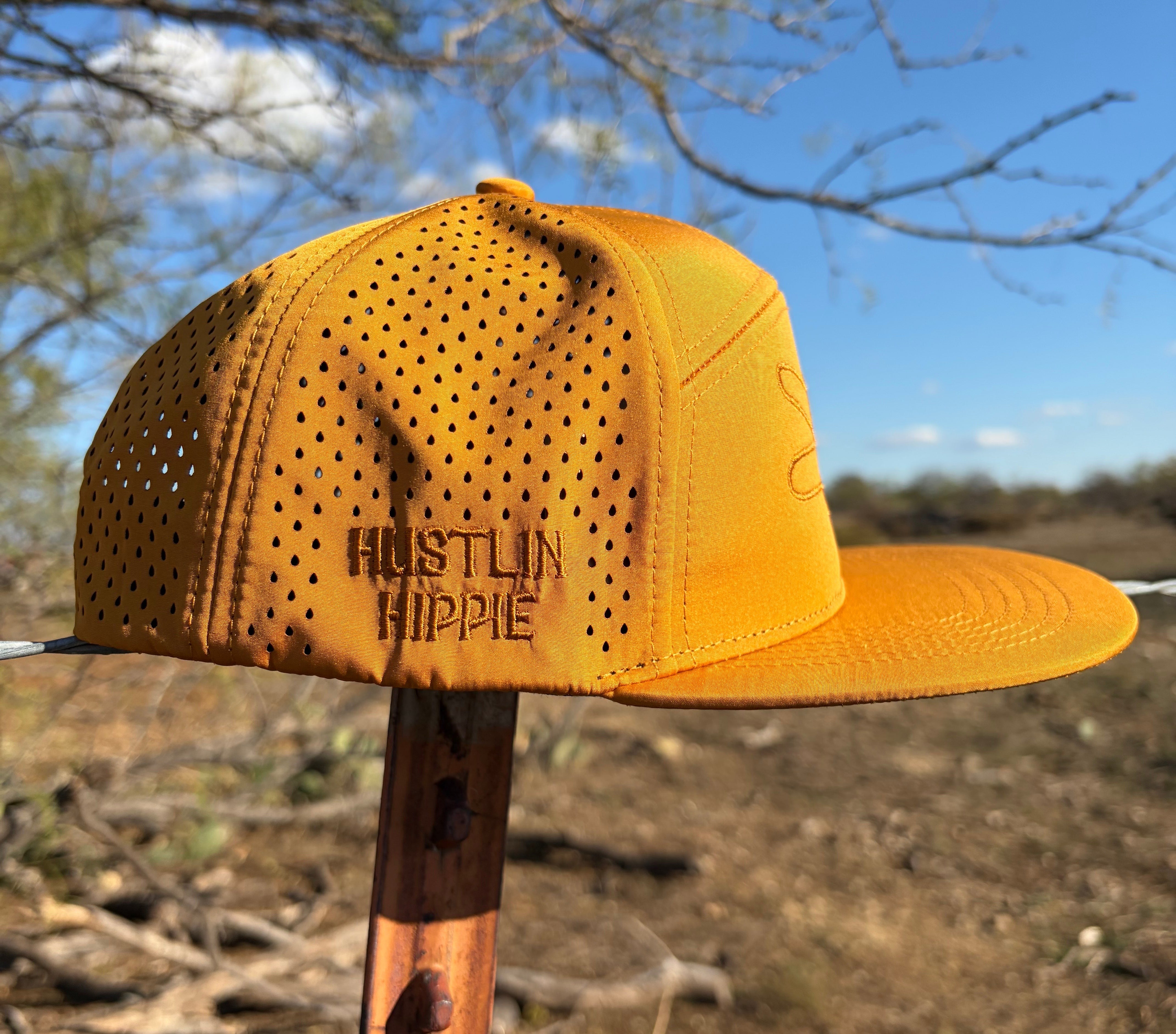 Back side view of Hustlin Hippie Signature Burnt Orange Hydro Snapback Hat with laser perforated panels and embroidered Hustlin Hippie logo outdoors under blue sky