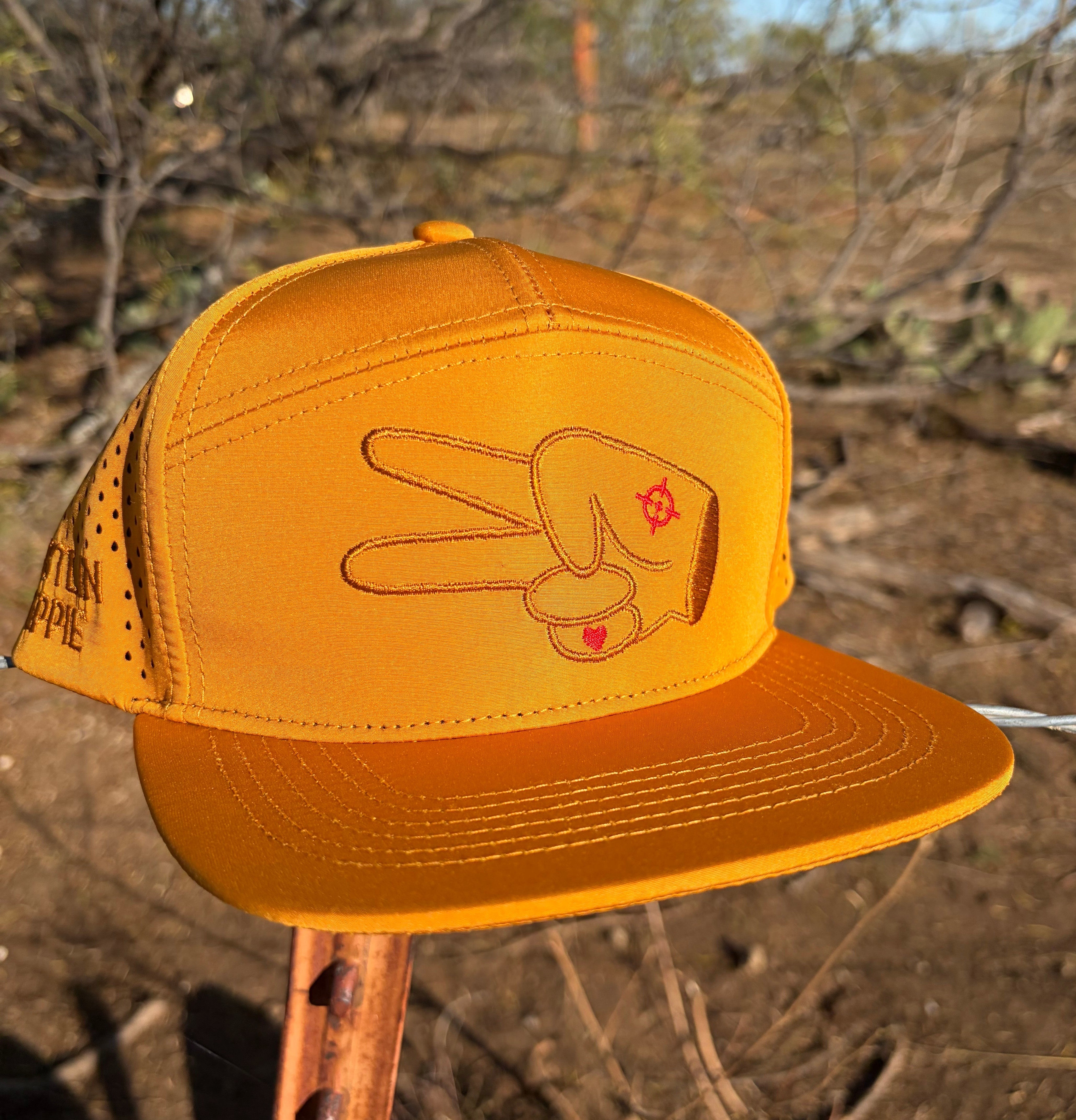 Hustlin Hippie Signature Burnt Orange Hydro Snapback Hat with laser perforated panels displayed outdoors in rugged natural terrain