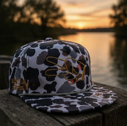 Hustlin Hippie Signature Midnight Camo rope snapback hat displayed beside a lake at sunset with warm outdoor adventure vibes.