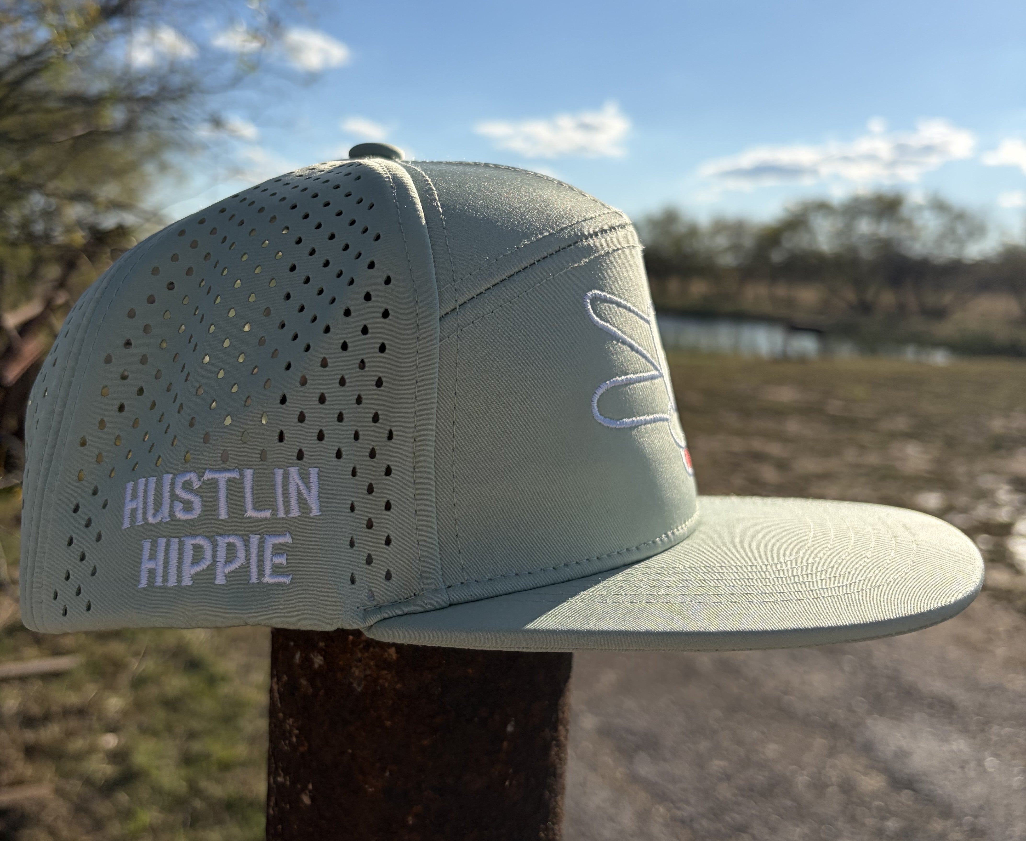 Side profile of the Signature Mint Green Hydro Snapback Hat with white Hustlin Hippie stitched branding and perforated hydro material.