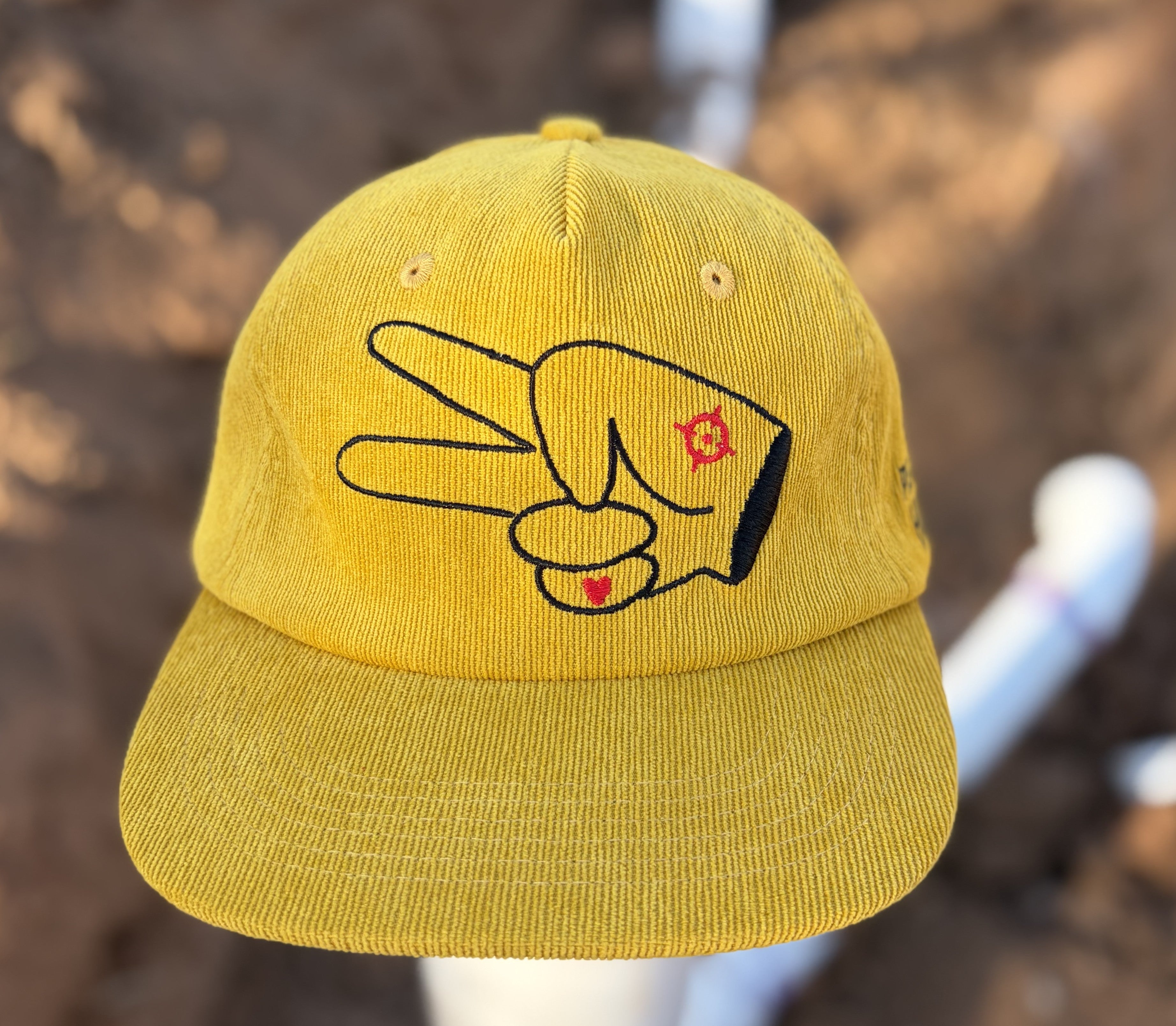 Front view of the Hustlin Hippie Signature Mustard Corduroy Snapback Hat with embroidered hand logo and flat bill design.