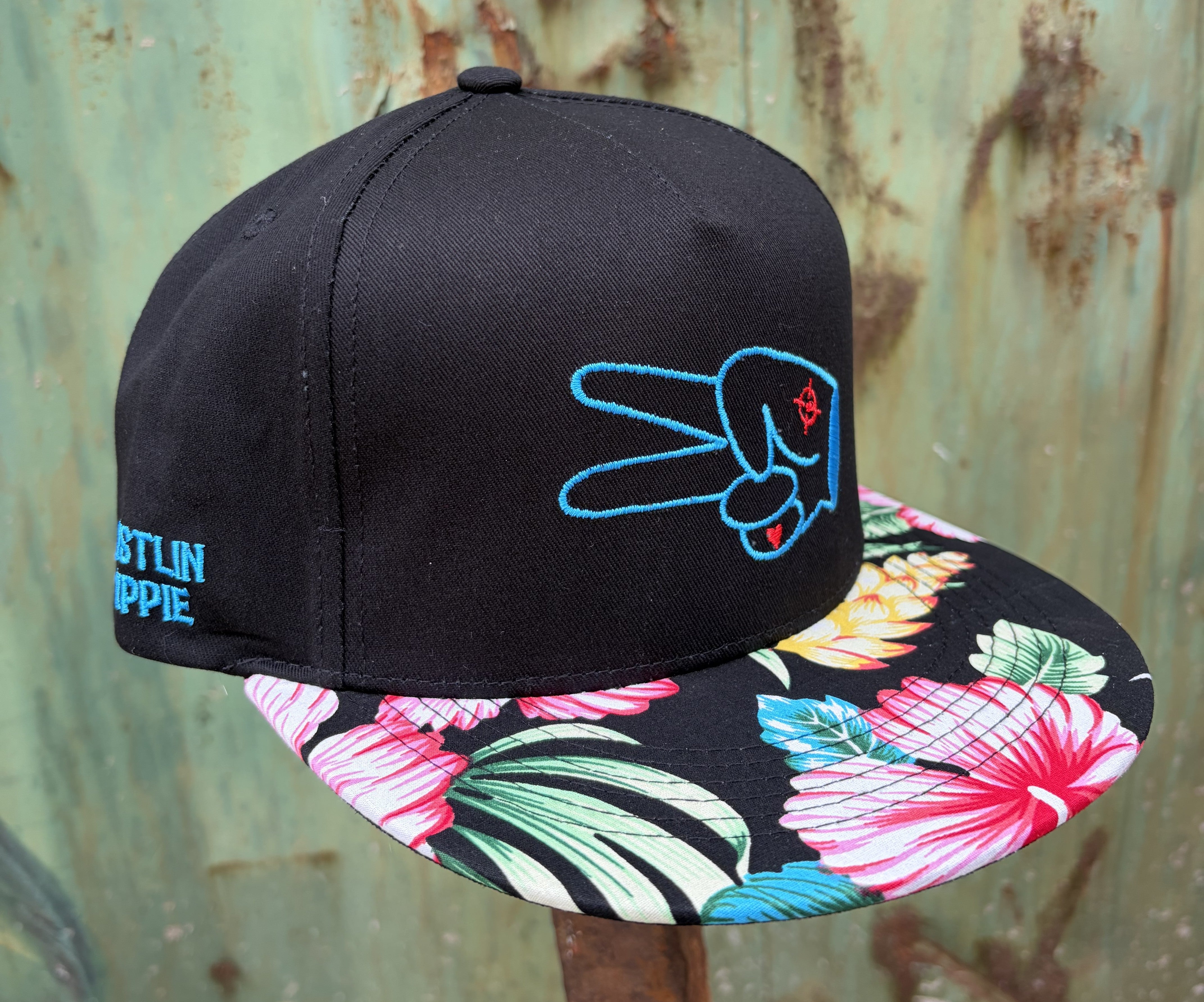 Angled view of the Hustlin Hippie Signature Tropical Floral flat bill snapback hat featuring tropical hibiscus print and embroidered signature logo.