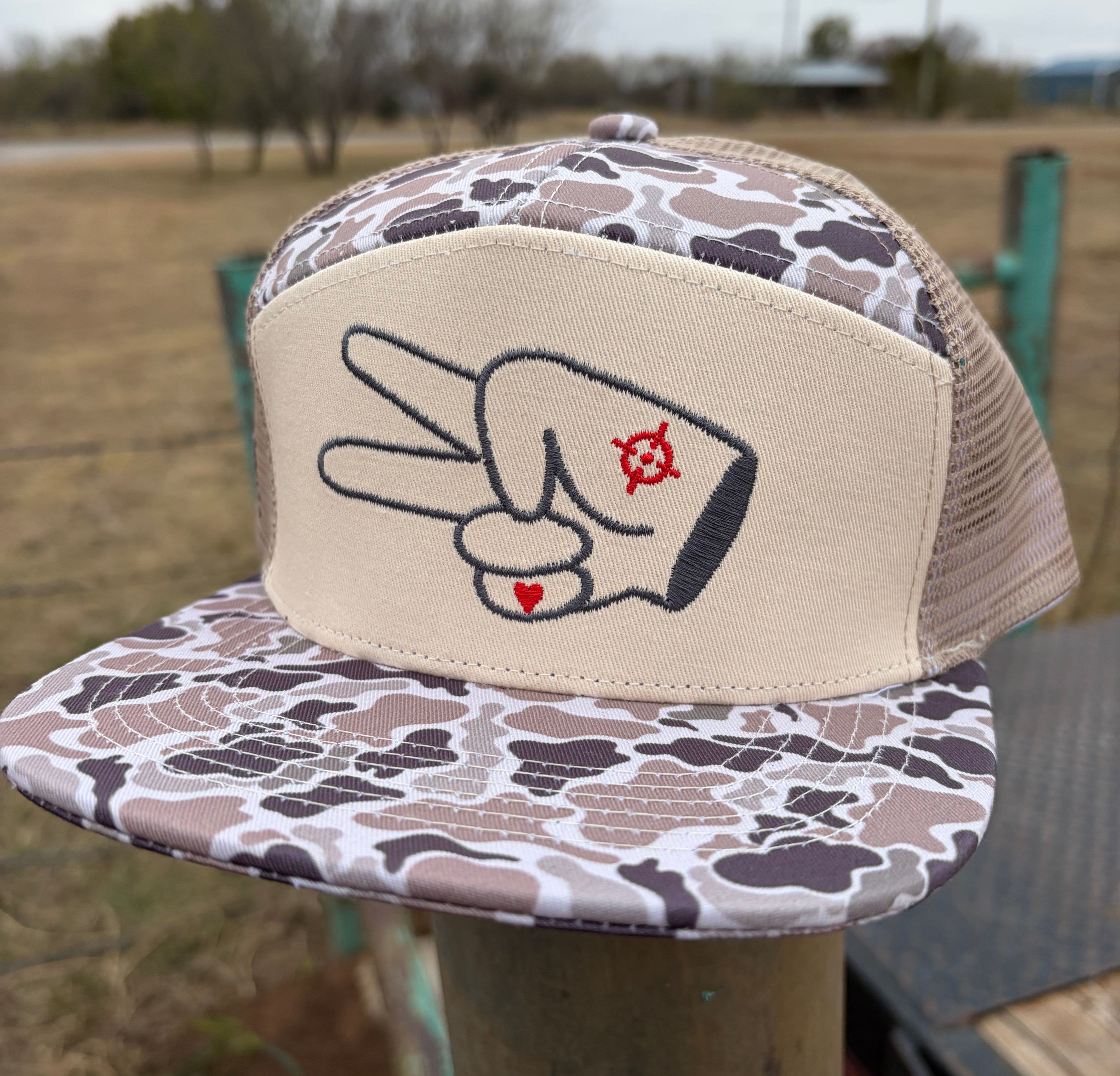 Front view of Hustlin Hippie tan camo 7 panel mesh back trucker hat with embroidered signature logo