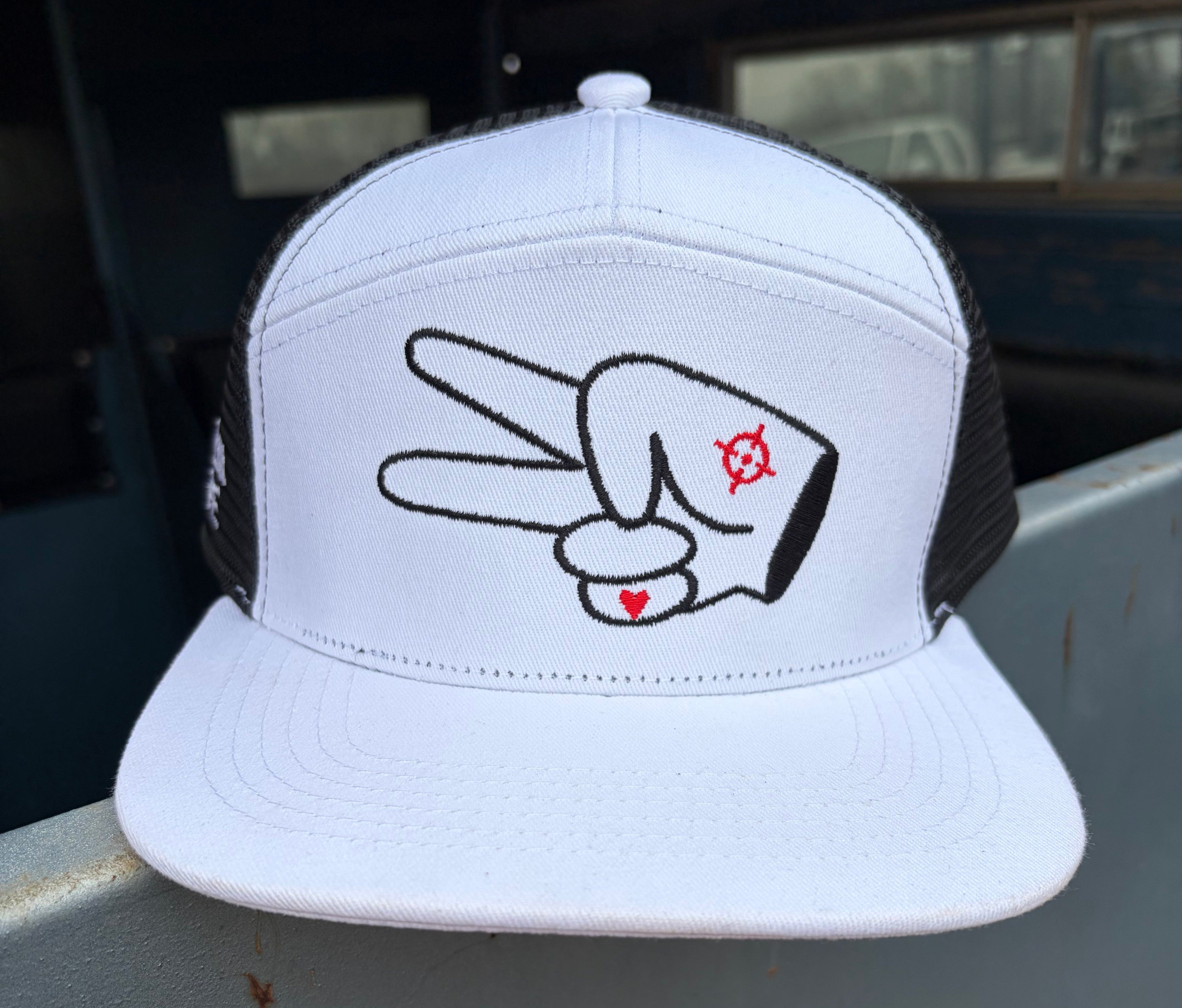 Front angle view of a white and black Hustlin Hippie flat bill mesh trucker snapback hat with embroidered signature peace sign logo.