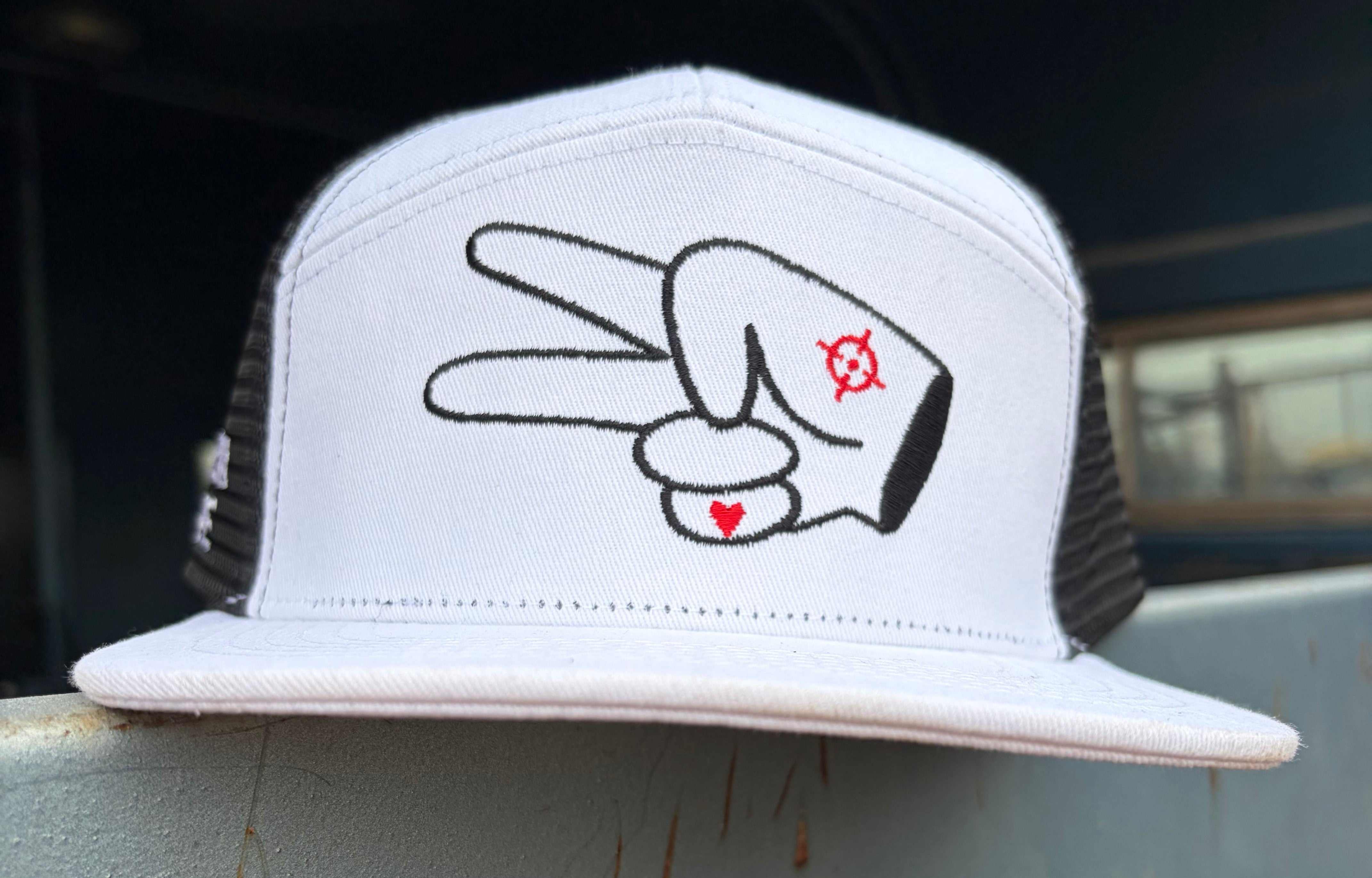 Front view of a white and black Hustlin Hippie mesh trucker snapback hat featuring the signature peace sign logo embroidered on the front panel.