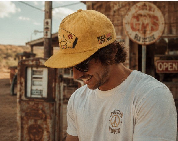 Retro road trip lifestyle photo featuring a mustard yellow Hustlin Hippie corduroy flat bill snapback hat and vintage desert vibes.