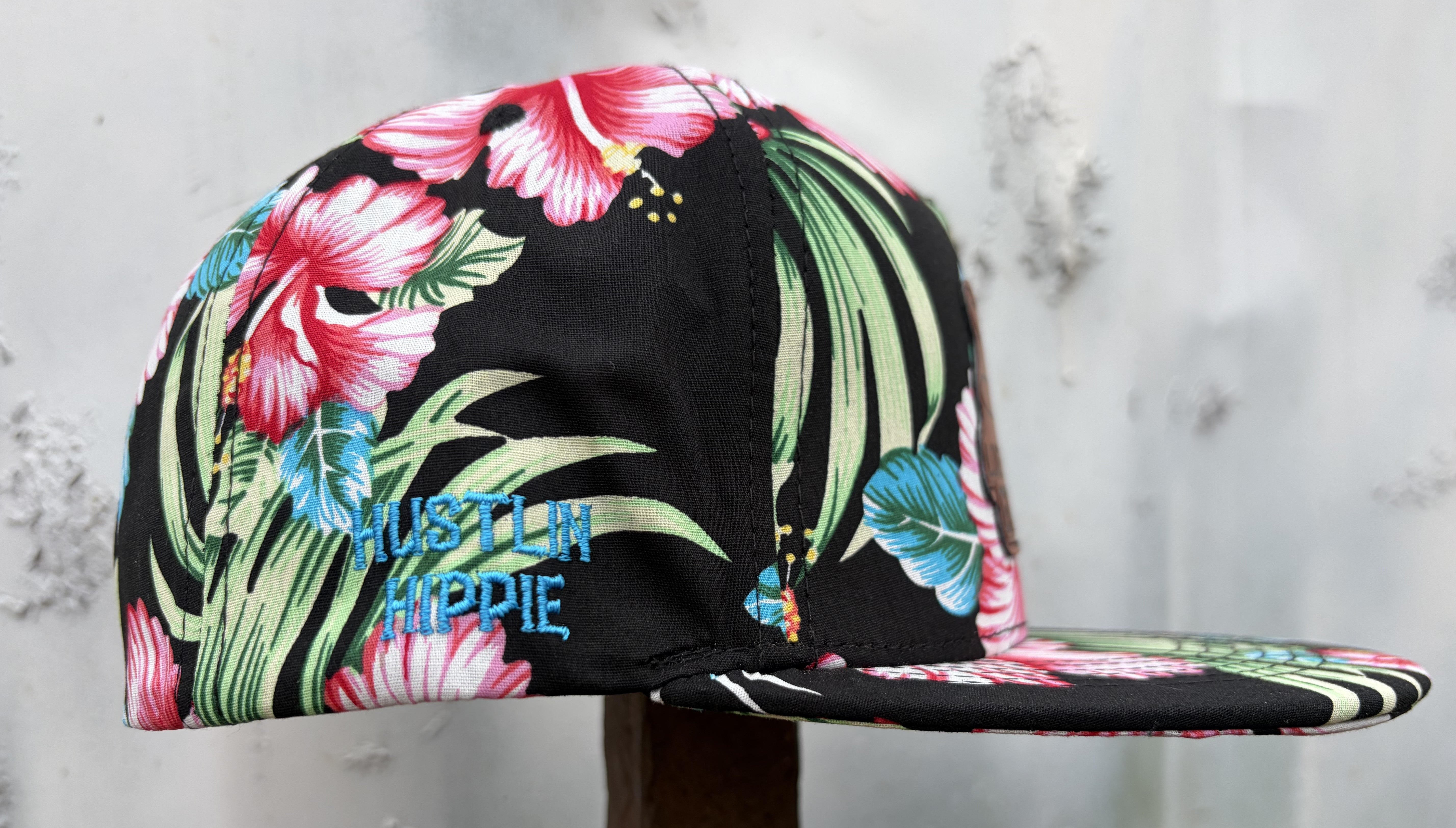 Side profile of tropical floral 5 panel snapback hat with Hustlin Hippie embroidery and vibrant island print.