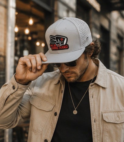 Man wearing gray Love Big Grind Hard hydro snapback hat with casual streetwear outfit in downtown city setting