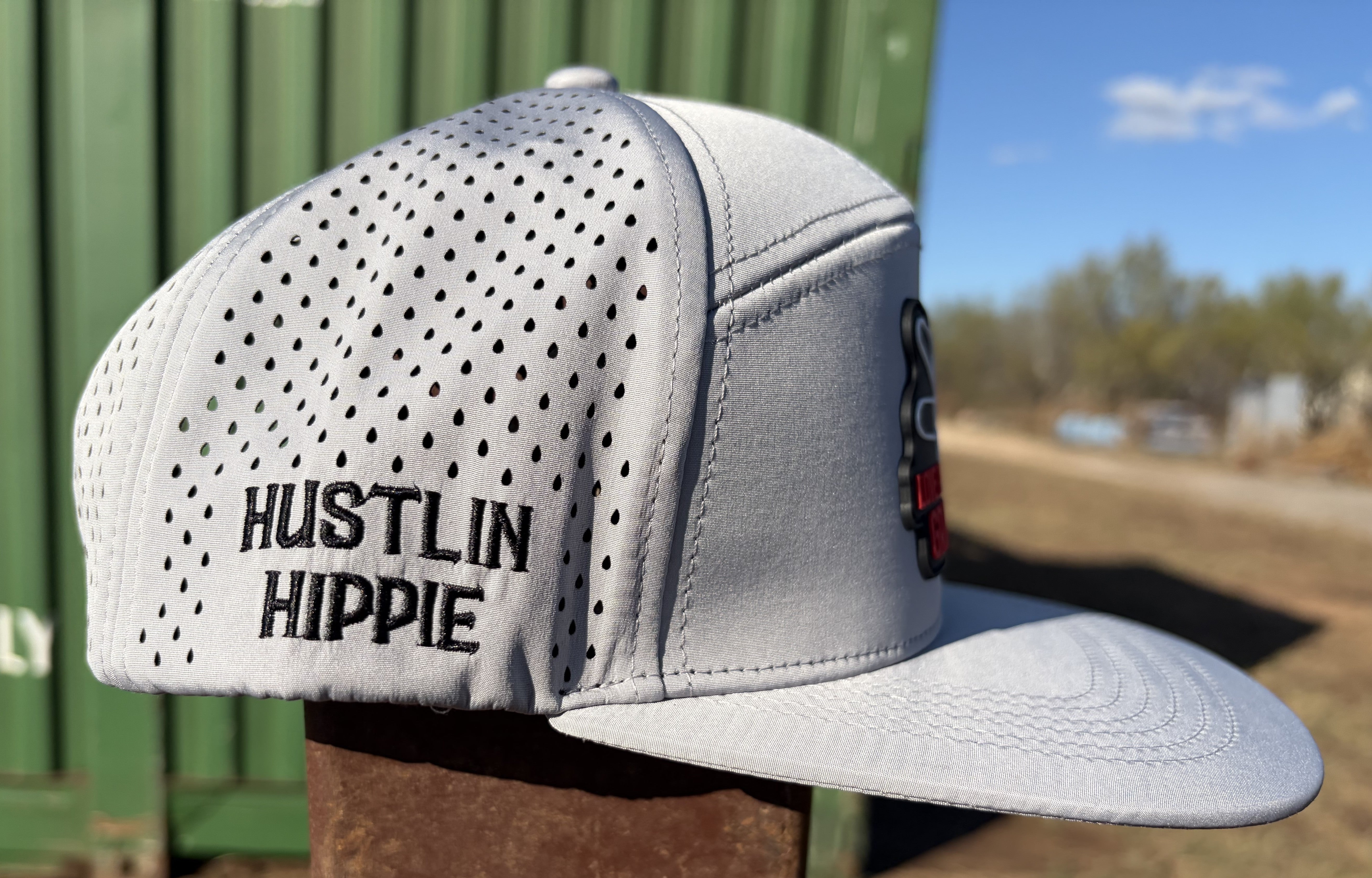 Side profile of gray Hustlin Hippie hydro performance snapback hat with laser perforated panels and rubber patch