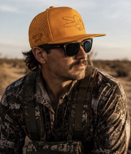 Hunter wearing a golden burnt orange Hustlin Hippie hydro snapback in the outdoors with rugged western and backcountry style.