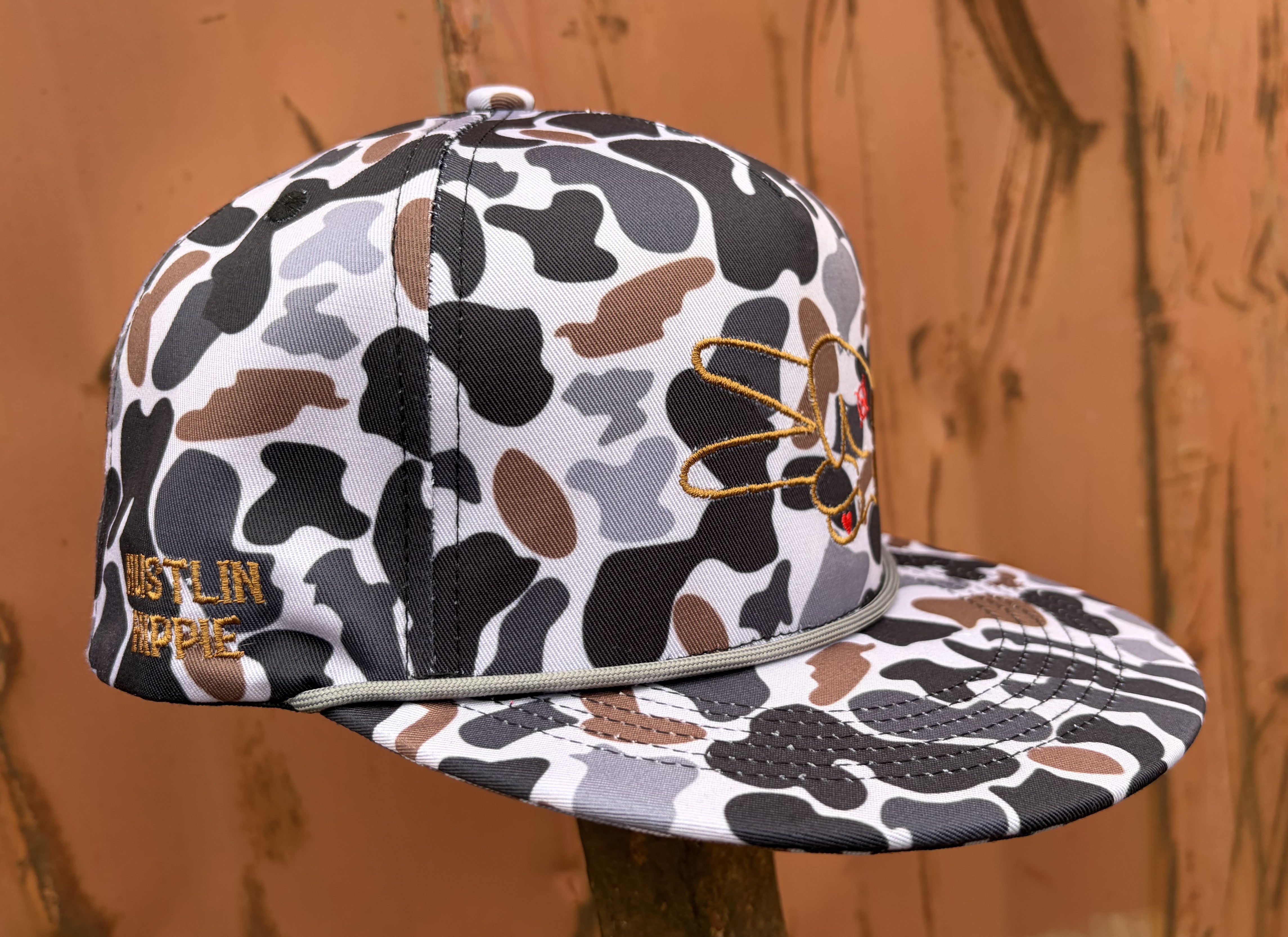 Side profile of the Hustlin Hippie Signature Midnight Camo rope snapback hat featuring embroidered Hustlin Hippie branding and full camo pattern.