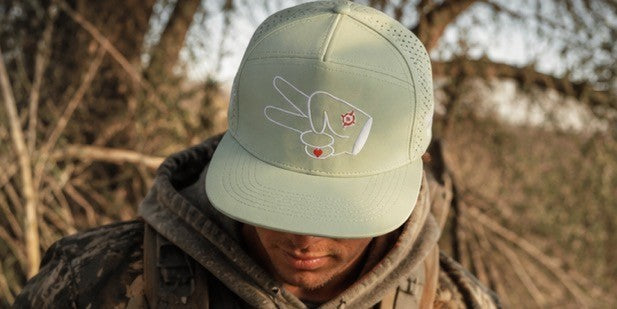 Outdoor lifestyle photo featuring the Signature Mint Green Hydro Snapback Hat worn in a rugged countryside setting.