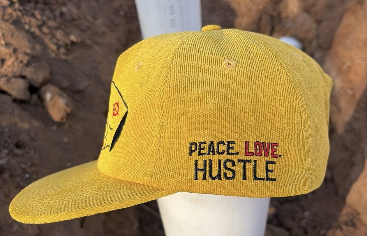 Side profile of the Hustlin Hippie Signature Mustard Corduroy Snapback Hat featuring PEACE LOVE HUSTLE embroidery.