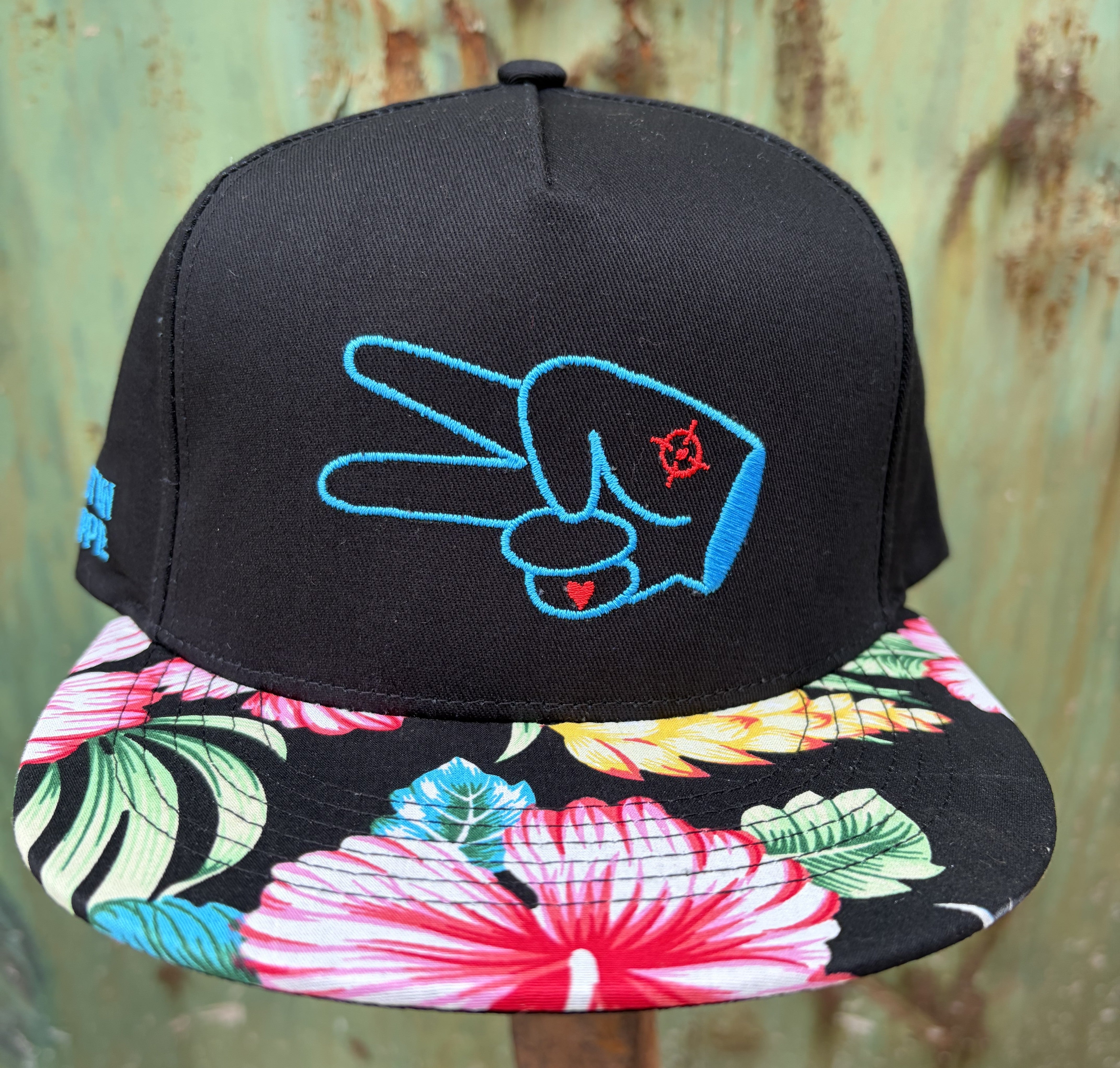 Front view of the Hustlin Hippie Signature Tropical Floral snapback hat with bright blue embroidered logo and tropical floral brim.